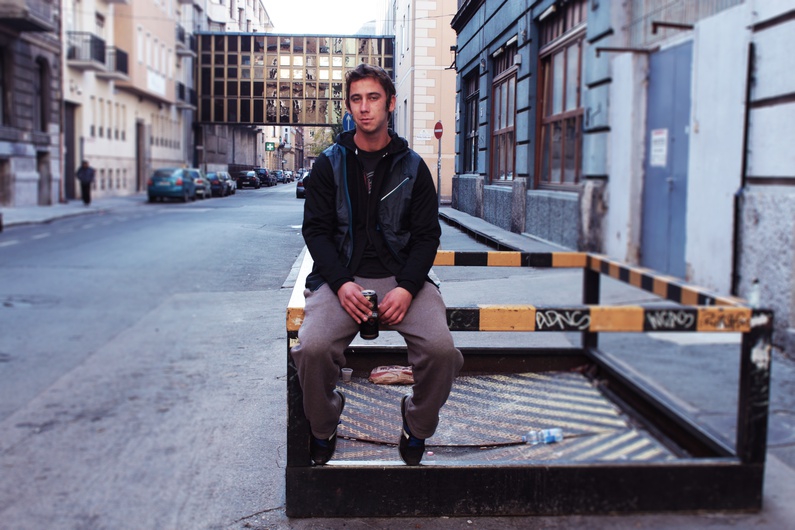 A guy takes a break in the street next to MÜSZI